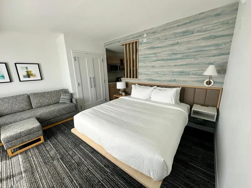 Une chambre d'hotel avec un canapé, un lit et une décoration murale abstraite.