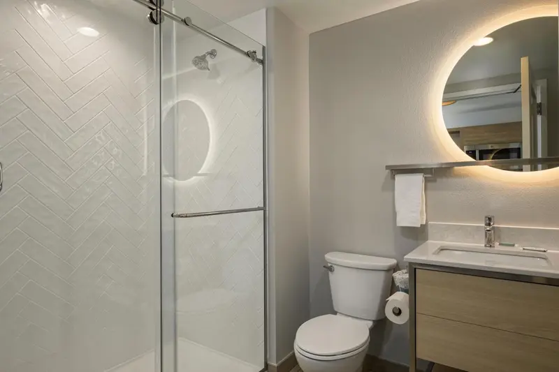 Une salle de bain moderne avec douche à l'italienne et miroir lumineux.