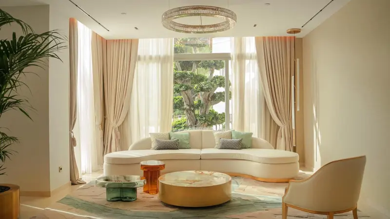 Un salon lumineux avec un canapé incurvé et une grande fenêtre.