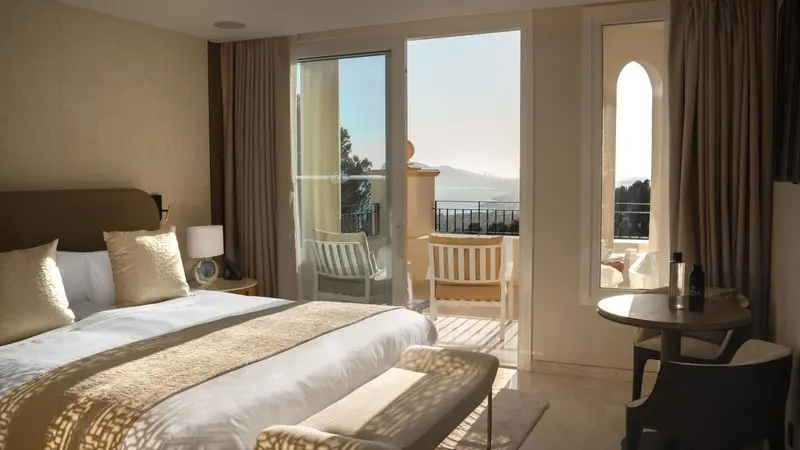 Une chambre lumineuse s'ouvre sur une terrasse avec vue sur la mer.
