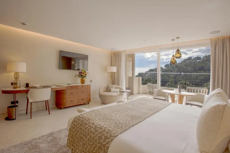 Chambre lumineuse avec un grand lit et un accès à une terrasse.