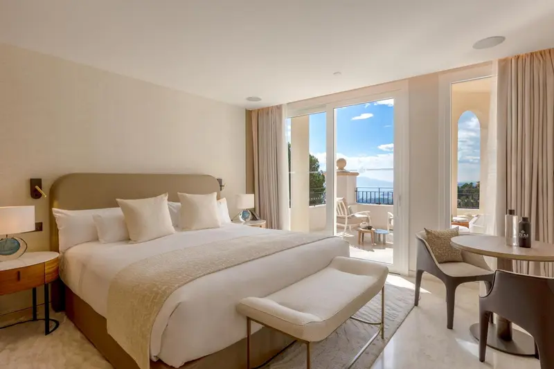 Une chambre lumineuse avec un grand lit et un accès à un balcon.