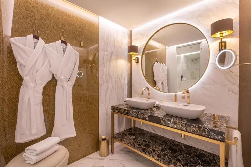 Une salle de bain moderne avec deux vasques et des peignoirs blancs.