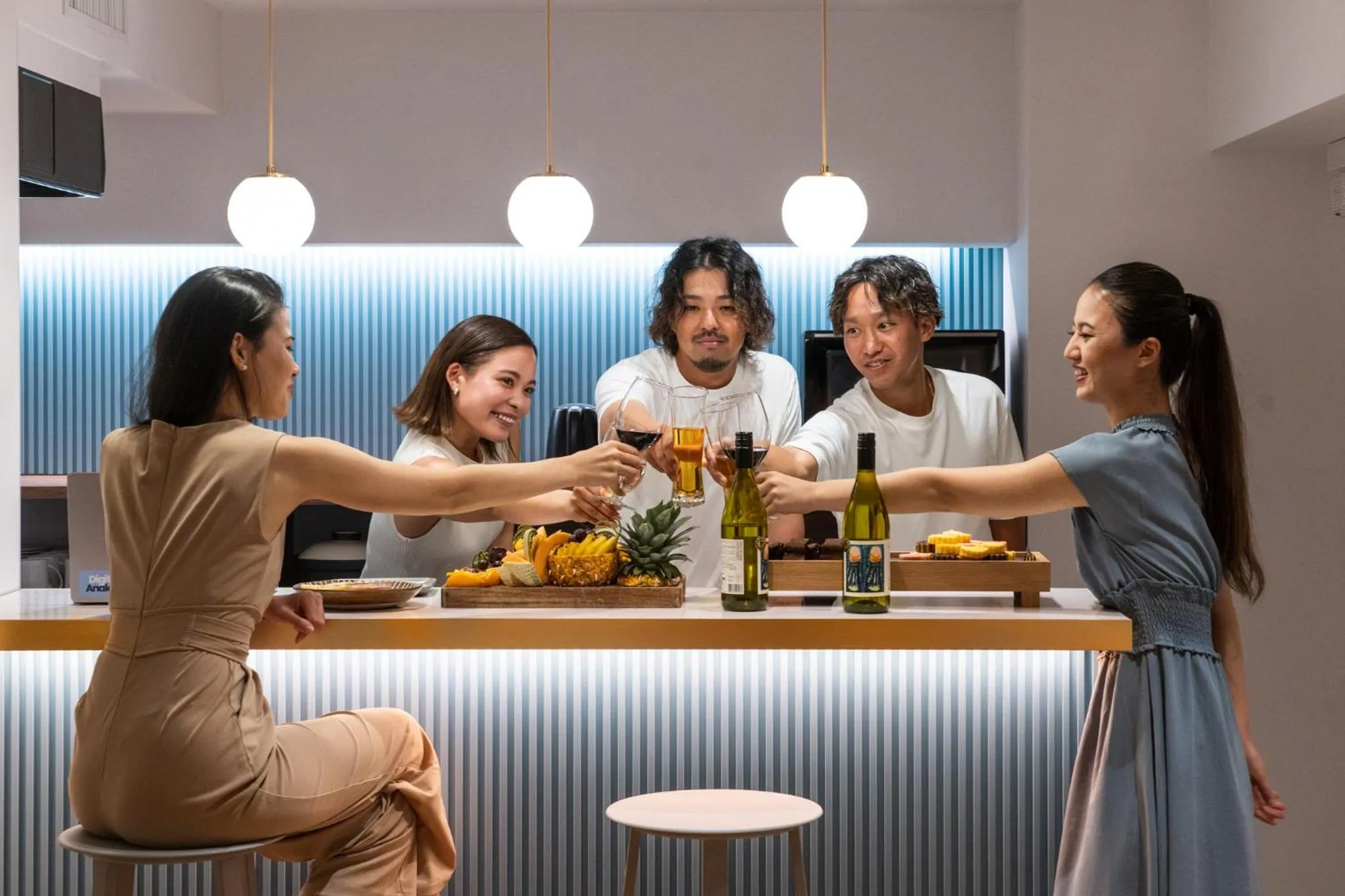 Un groupe de personnes trinque avec des verres et des bouteilles autour d'un comptoir.