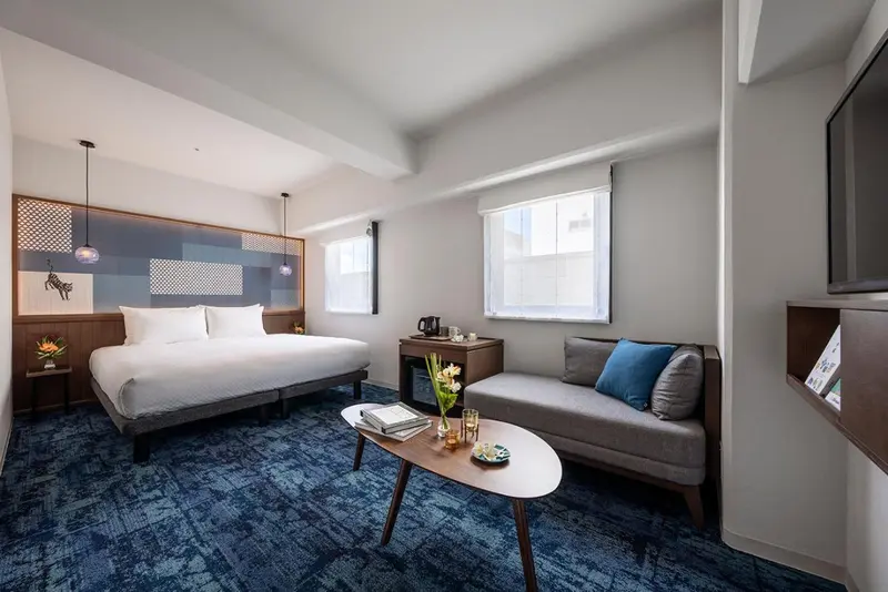 Une chambre lumineuse avec un lit double et un coin salon.