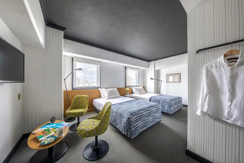 Chambre lumineuse avec deux lits simples et un coin lecture.
