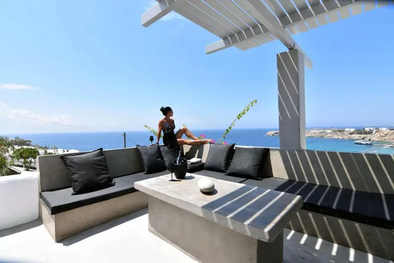 Une personne assise sur un canapé extérieur avec vue sur la mer.