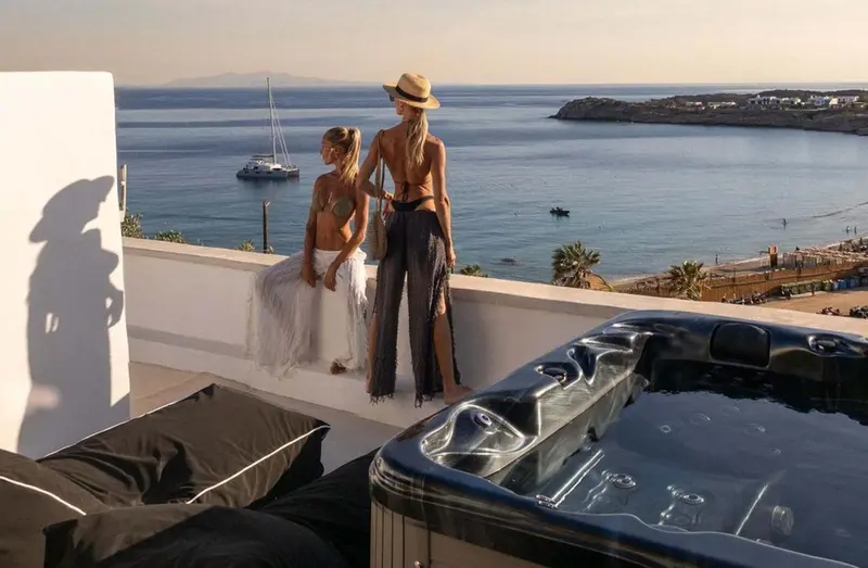 Deux femmes regardent la mer depuis une terrasse avec un jacuzzi.