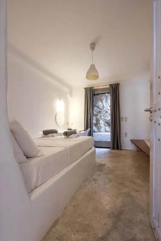 Une chambre lumineuse avec un lit blanc et un accès à une terrasse.