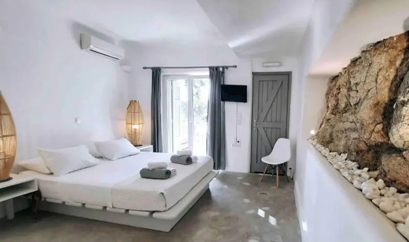 Une chambre lumineuse avec un grand lit et un mur en pierre.