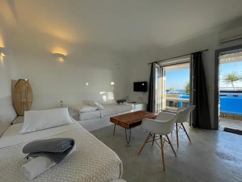 Une chambre lumineuse s'ouvre sur une terrasse avec vue sur la mer.