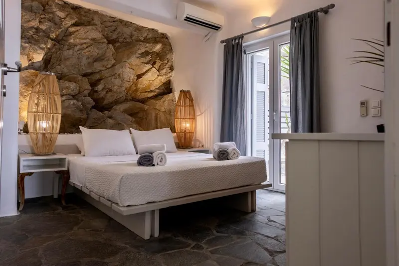 Une chambre lumineuse avec un lit double et un mur en pierre.
