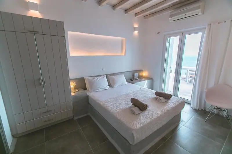 Une chambre lumineuse avec un grand lit et un accès à une terrasse.