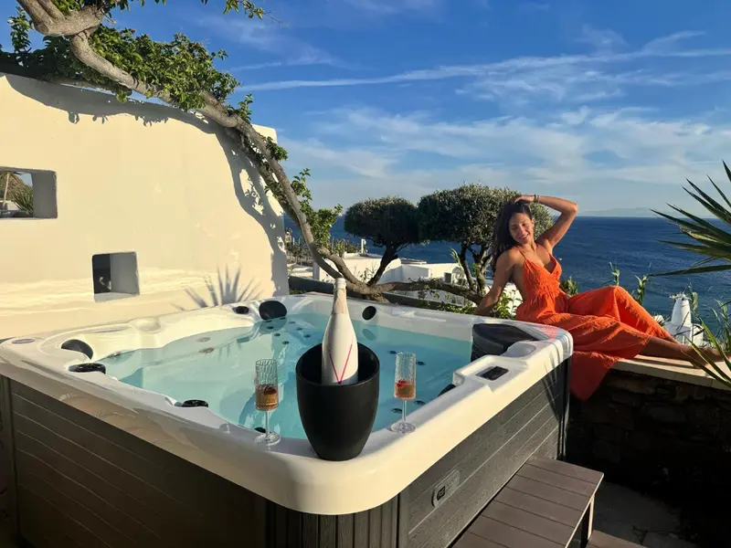 Une femme se détend au bord d'un jacuzzi avec vue sur la mer.