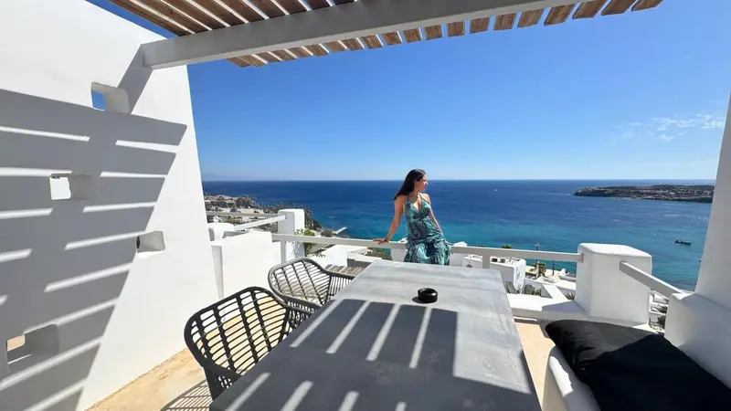 Une femme se tient sur une terrasse avec vue sur la mer.