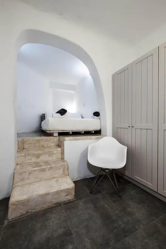 Une chambre à coucher avec un lit intégré dans une alcôve en pierre.