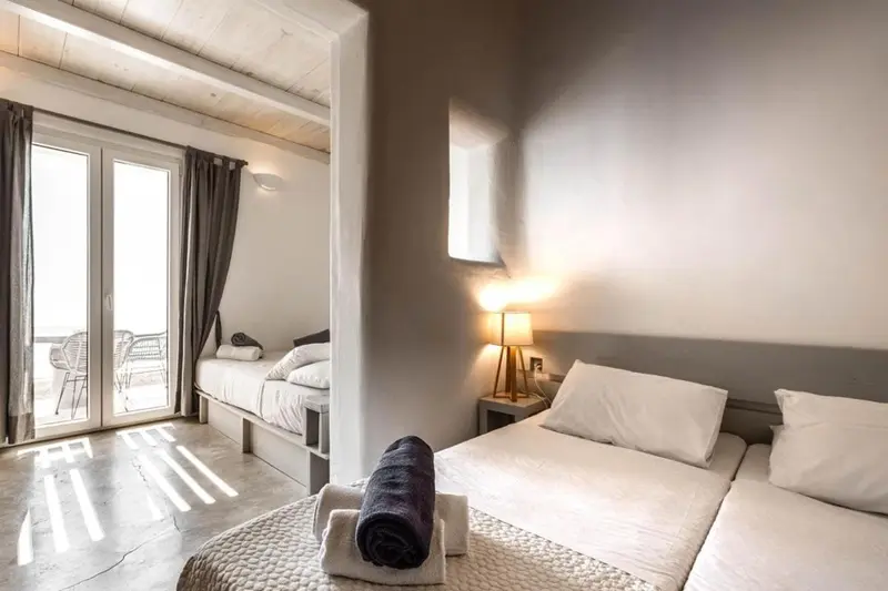 Une chambre lumineuse avec deux lits simples et un lit double.
