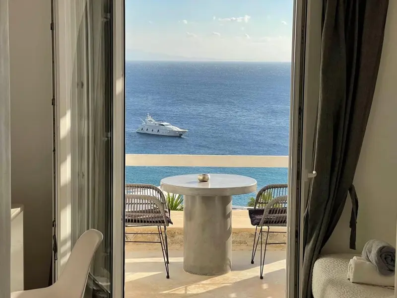 Vue sur la mer depuis une terrasse avec table et chaises.