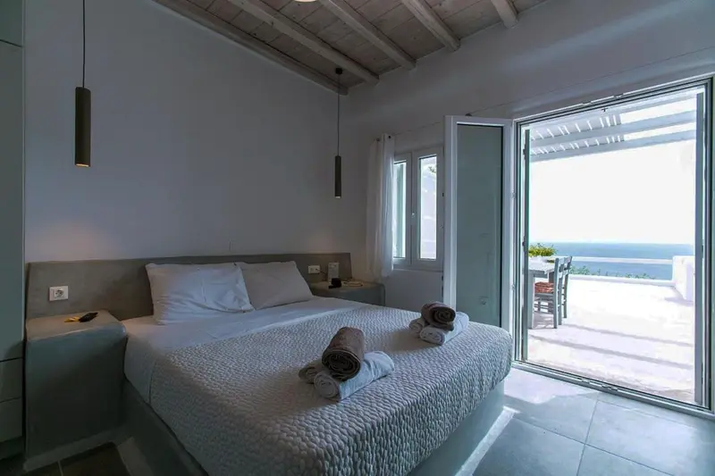 Une chambre lumineuse avec un grand lit donnant sur une terrasse.