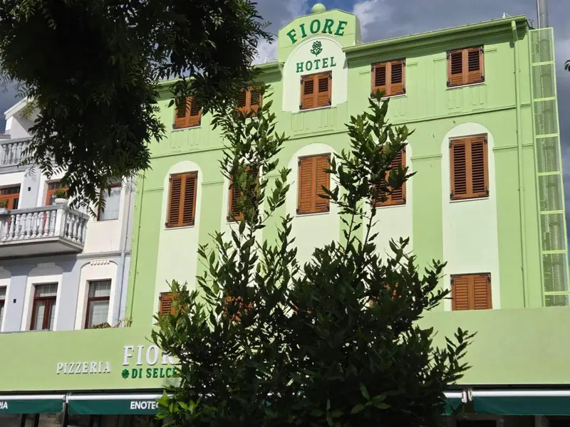 Façade d'un bâtiment vert à plusieurs étages avec des fenêtres et des balcons.