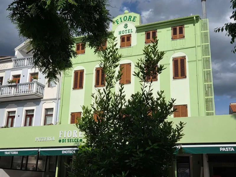 Façade d'un bâtiment vert à plusieurs étages avec des fenêtres et des balcons.