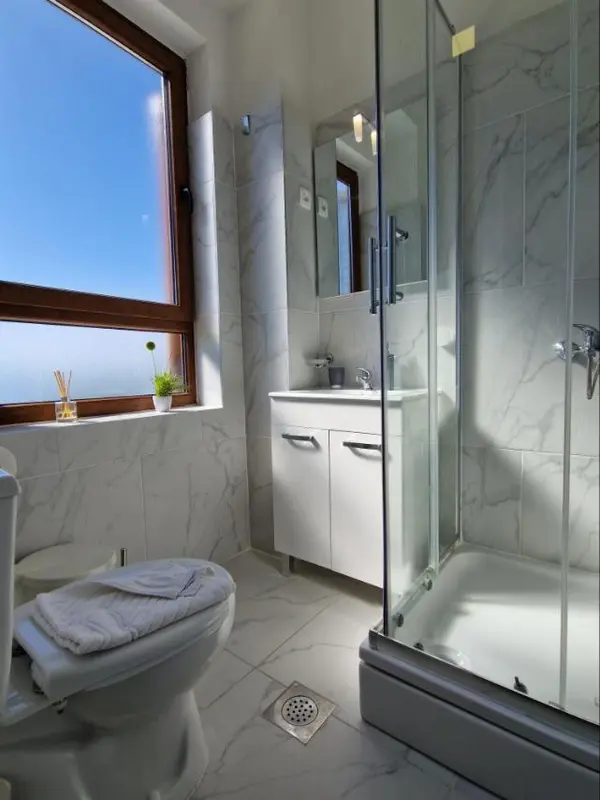 Une salle de bain lumineuse avec douche vitrée et carrelage mural.