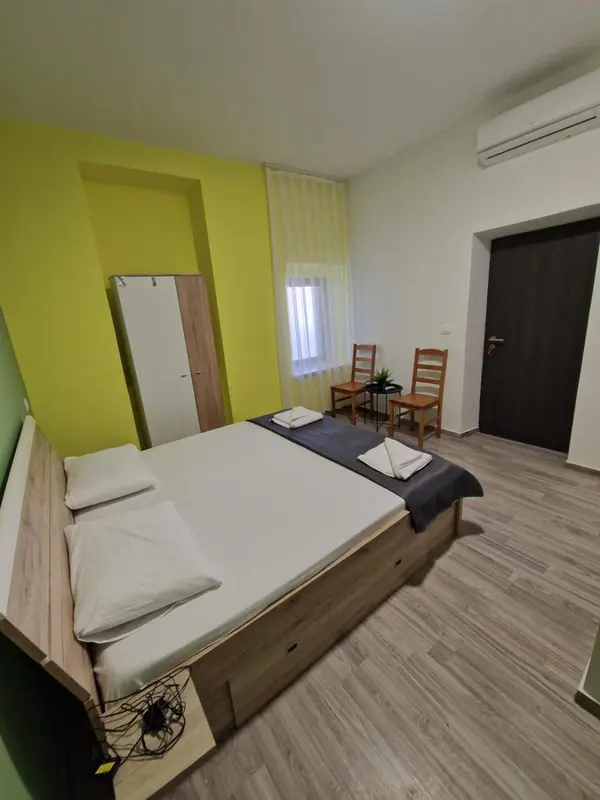 Une chambre lumineuse avec un lit double et une armoire.