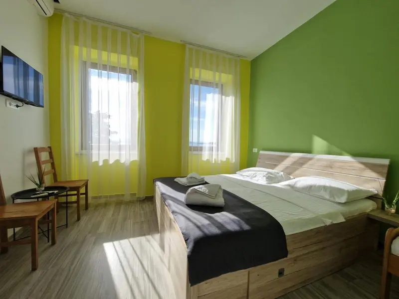 Une chambre lumineuse avec un lit double et deux fauteuils.