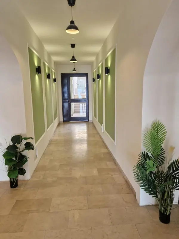 Couloir intérieur lumineux avec des murs verts et un sol carrelé.