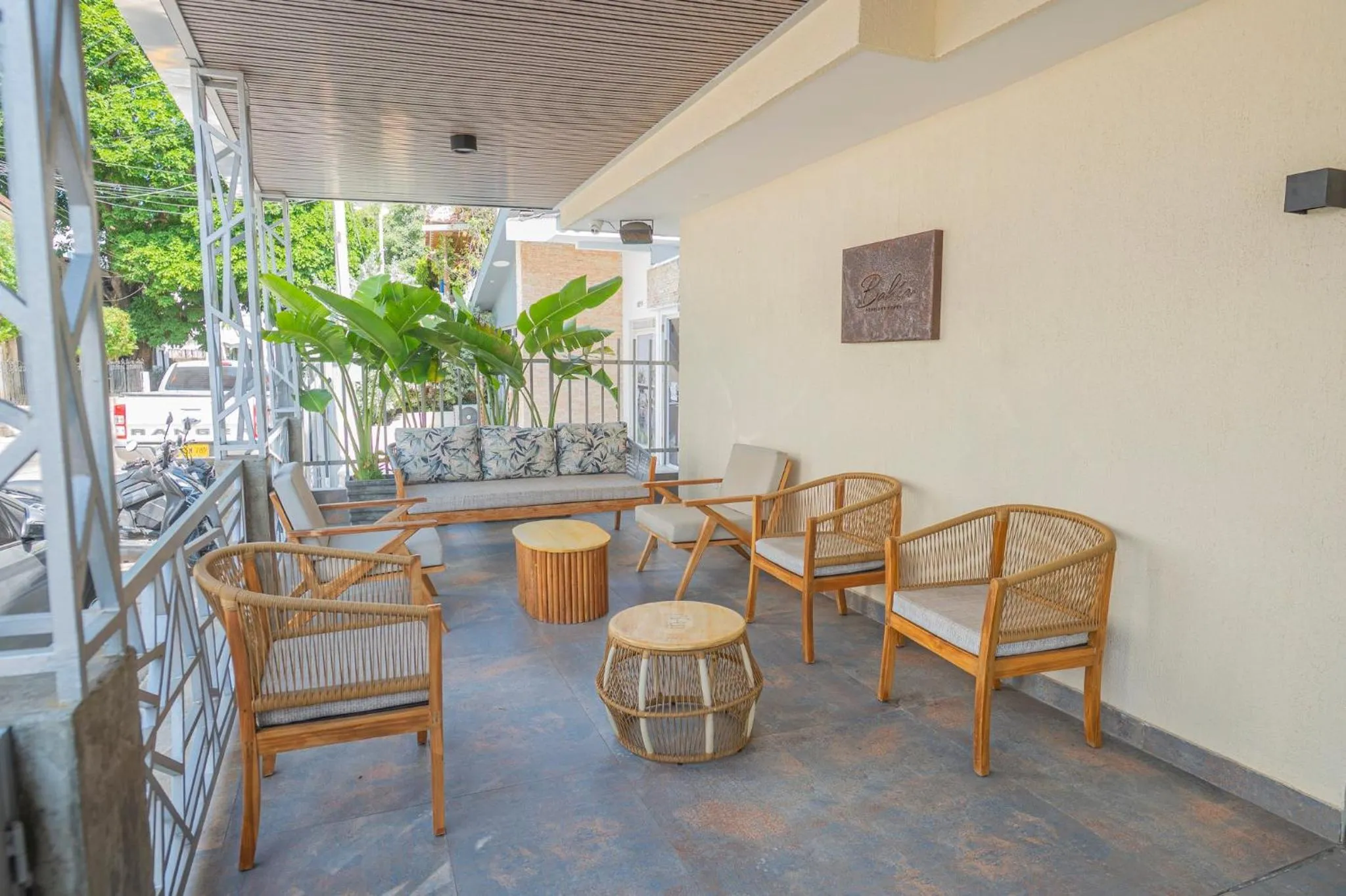 Espace de détente extérieur avec mobilier en rotin et plantes tropicales.