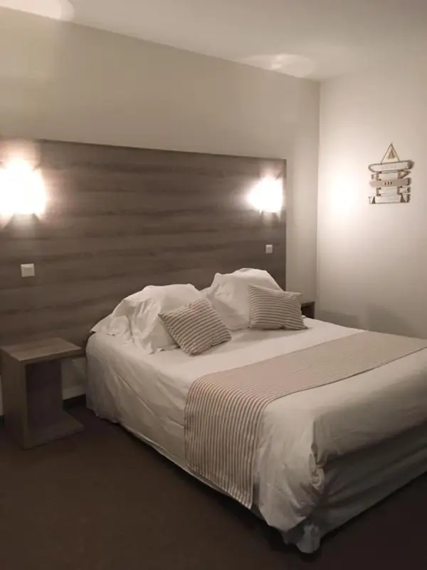 Une chambre avec un grand lit recouvert d'une couette blanche et de coussins.