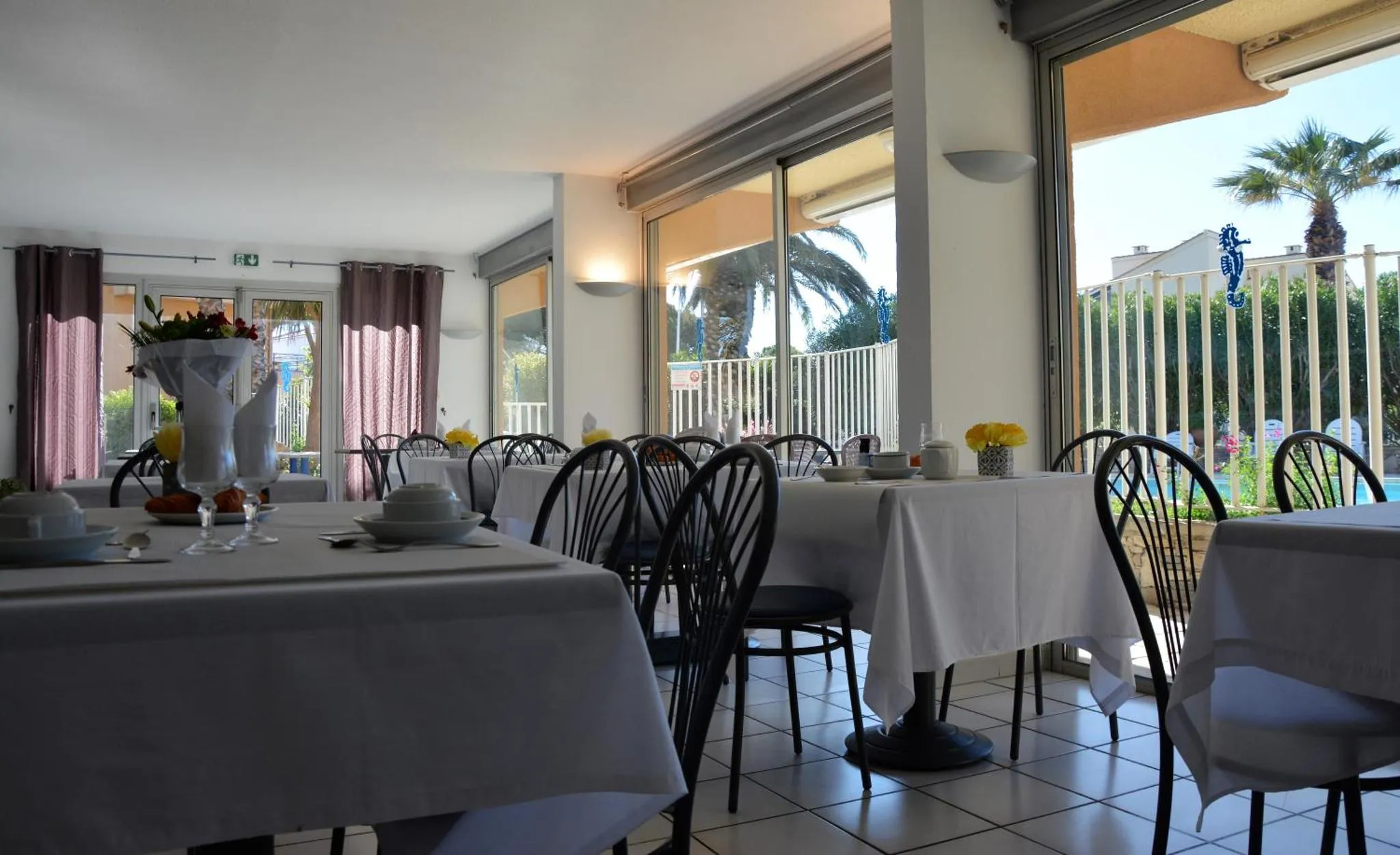 Une salle lumineuse avec des tables dressées pour le repas.