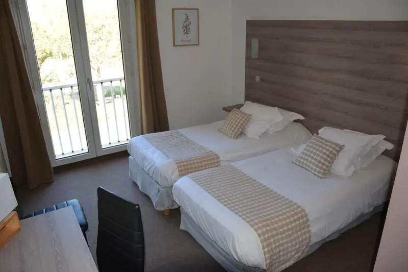 Chambre avec deux lits simples et vue sur l'extérieur.