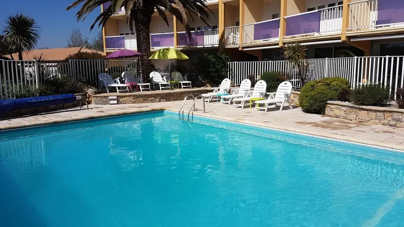 Piscine ensoleillée avec transats et végétation luxuriante.