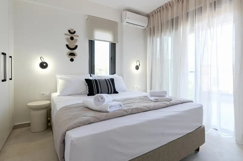 Une chambre lumineuse avec un grand lit et des rideaux clairs.