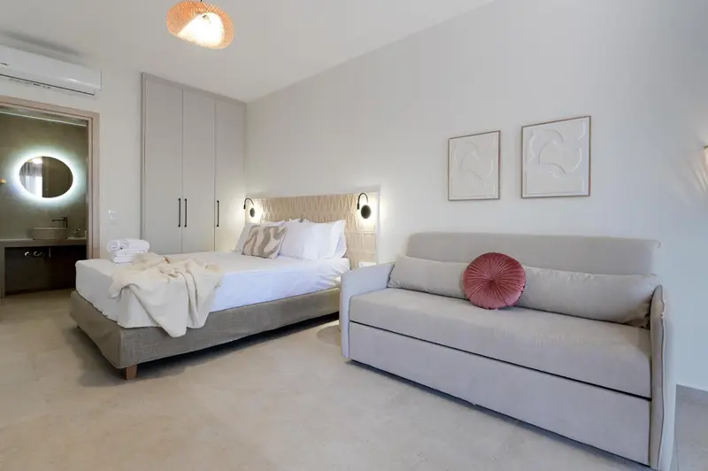 Une chambre lumineuse avec un grand lit et un canapé-lit.