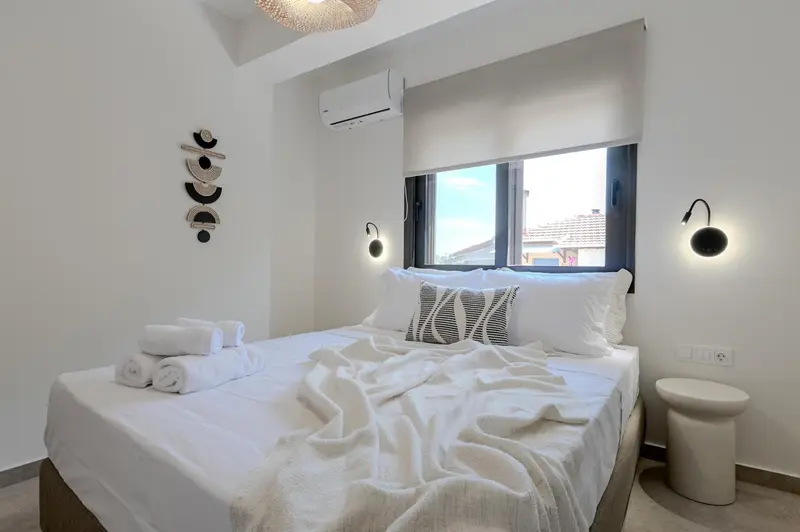 Une chambre lumineuse avec un grand lit recouvert d'une couverture blanche et de coussins.
