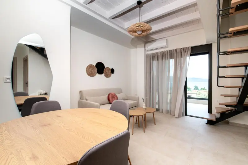 Espace de vie lumineux avec canapé, table basse et salle à manger.