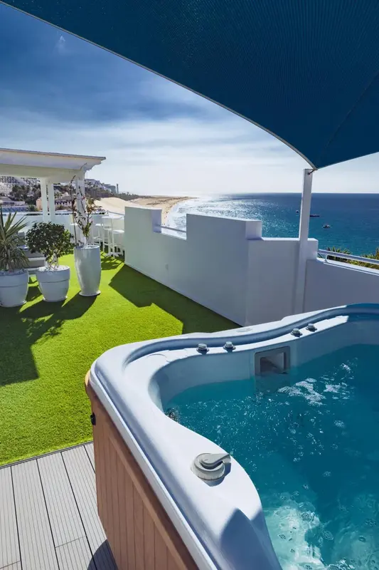 Un jacuzzi sur une terrasse avec vue sur la mer et la plage.