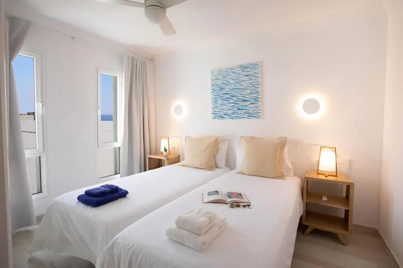 Une chambre lumineuse avec deux lits simples et une décoration sobre.