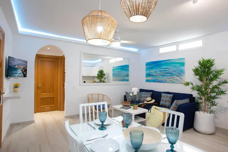 Espace de vie lumineux avec canapé bleu et table à manger.