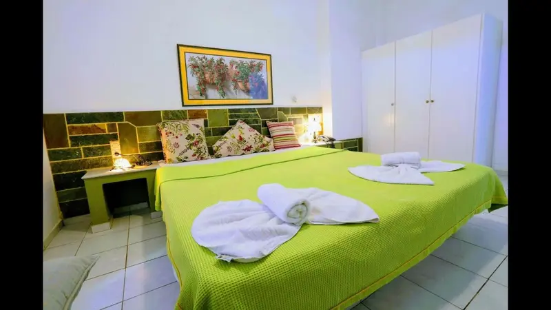 Une chambre lumineuse avec un grand lit recouvert de linge vert et blanc.