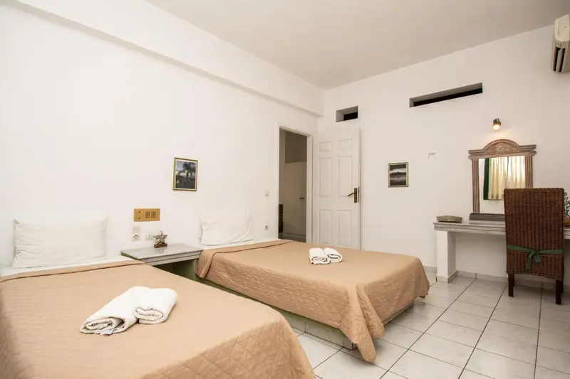 Une chambre lumineuse avec deux lits simples et une décoration sobre.