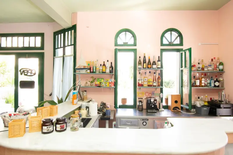 Un comptoir de bar blanc avec des bouteilles colorées en arrière-plan.