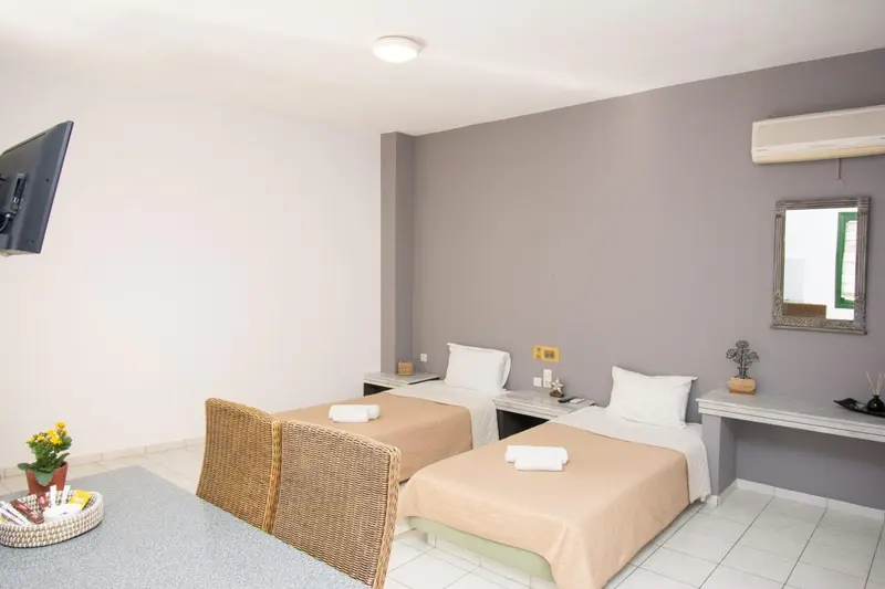 Une chambre lumineuse avec deux lits simples et un fauteuil en osier.