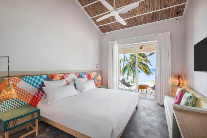 Chambre lumineuse avec un grand lit et vue sur la plage.