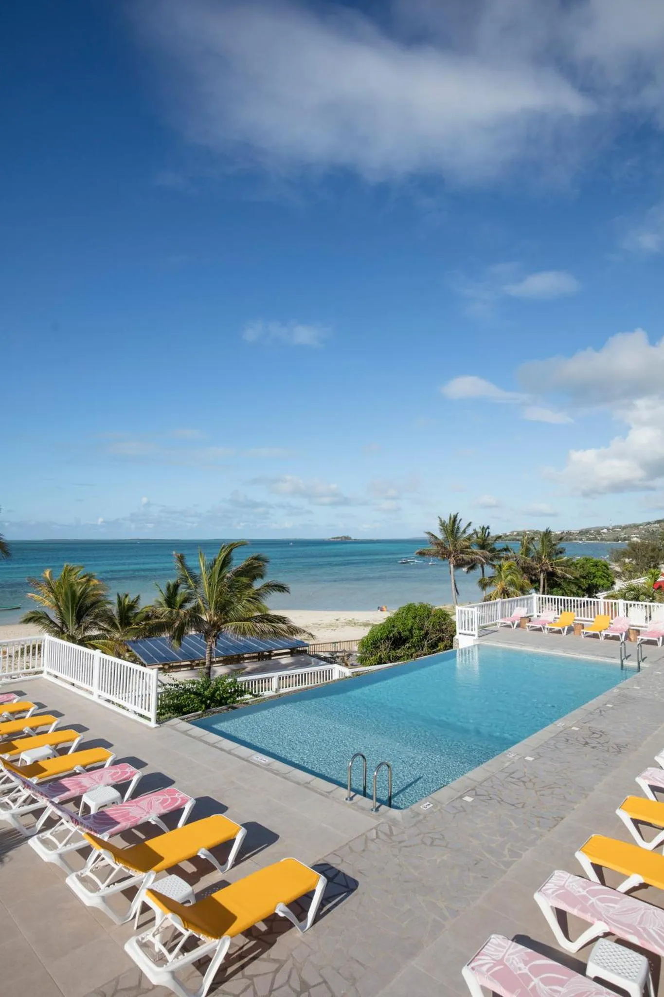 Transats colorés au bord d'une piscine à débordement avec vue sur la mer.