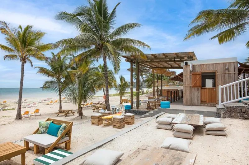Espace de détente en bord de mer avec mobilier en bois et coussins.