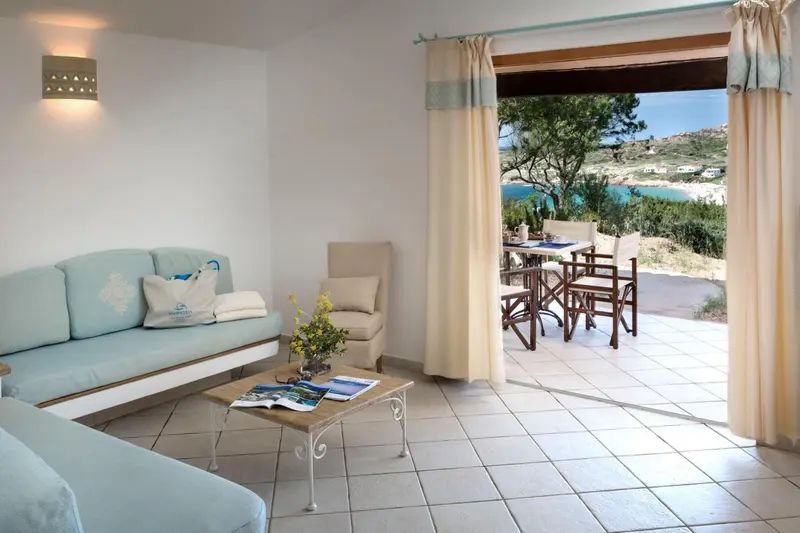 Espace de détente lumineux avec canapé et vue sur une terrasse et la mer.