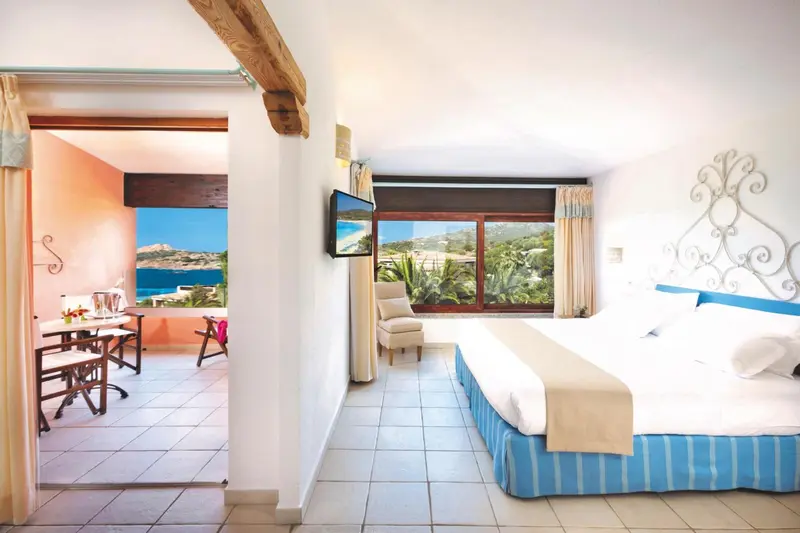 Une chambre lumineuse s'ouvre sur une vue mer et un espace repas.